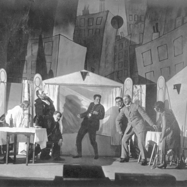 In Trommeln in der Nacht, Caspar Neher’s painted backdrop frames the action with stark, expressionist imagery, contrasted by sparse, realistic stage elements