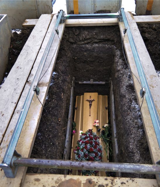 A coffin in an open grave before being covered with soil.