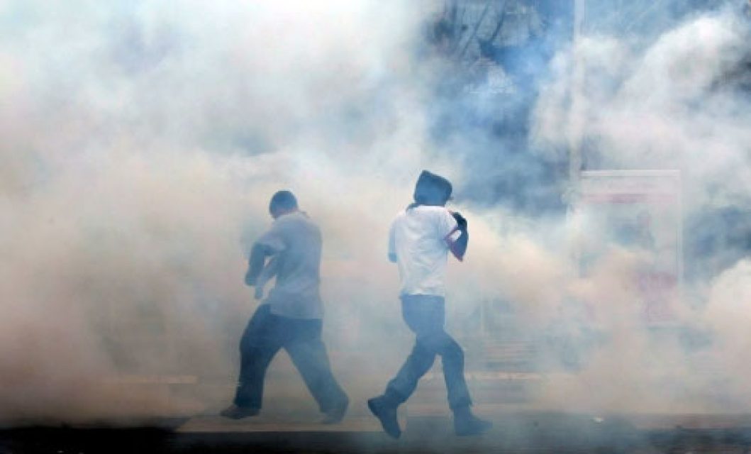 Manifestantes entre gas lacrimógeno.